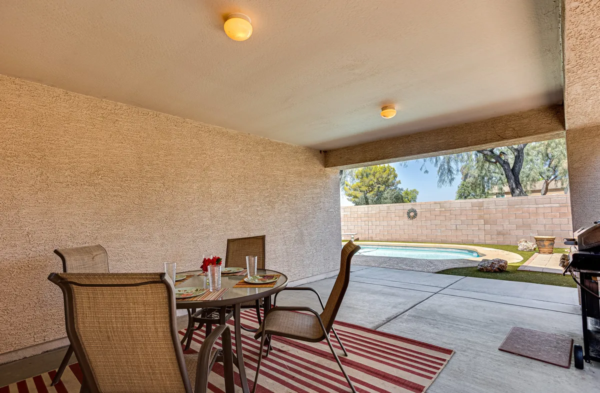 This image features a table with chairs set beside a pool, accented by decorative elements that enhance the inviting outdoor ambiance. The scene is set for outdoor dining, relaxing by the pool, or hosting social gatherings—moments that embody the leisurely, community-centric lifestyle described in the section.