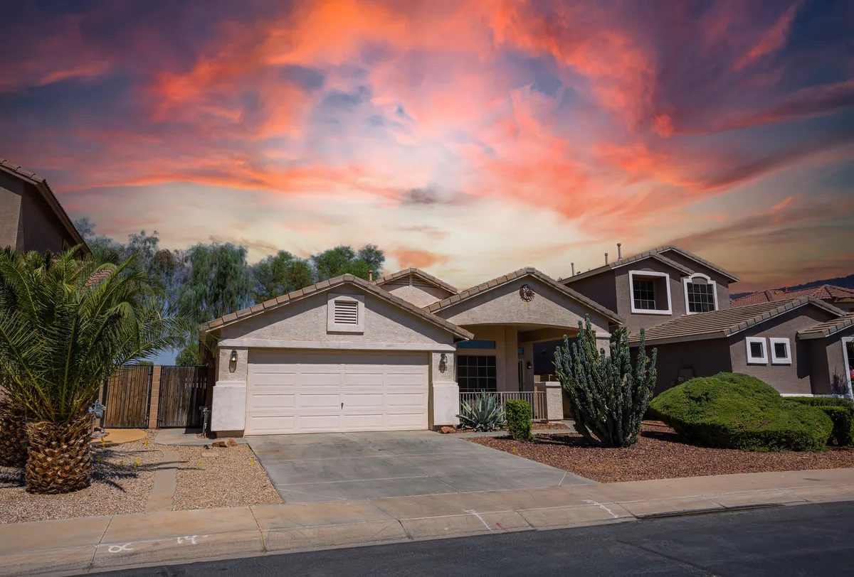 This exterior image displays a tranquil scene with palm trees, cacti, a garage door, and a welcoming front porch. The landscape is typical of a golf community in a desert setting, evoking the atmosphere guests would experience just outside their door.