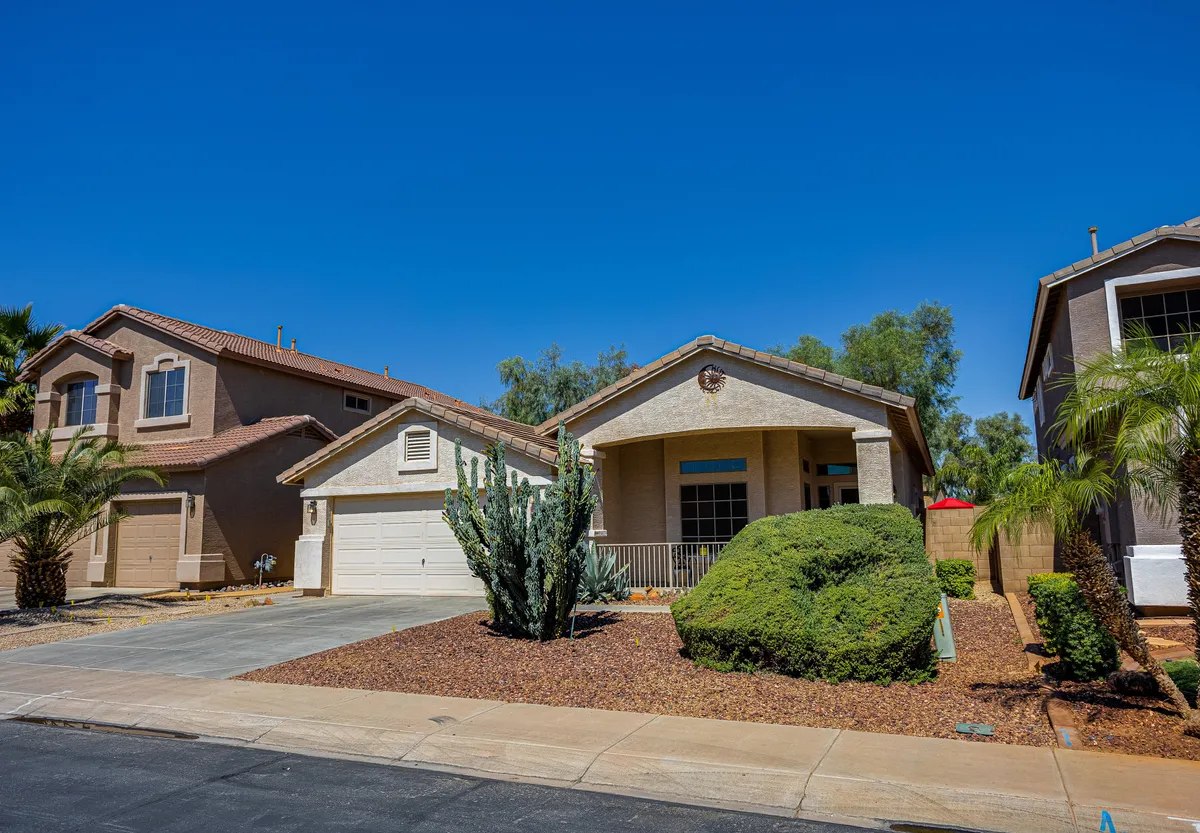 A welcoming exterior shot of the main house surrounded by a landscaped front yard, featuring cactus and palm trees. The scene hints at the property’s connection to the outdoors and desert landscape, with space for gatherings and relaxation.