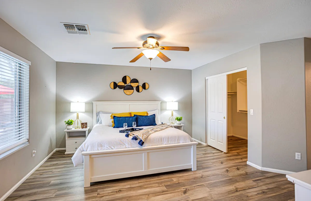 A queen-sized bed is centered against a wall adorned with decorative art. The room features nightstands on either side, each with a lamp, creating a comfortable and restful ambiance. The bedding is neatly arranged, and the atmosphere suggests a cozy, private escape, perfect for relaxation or enjoying a quiet moment with a book.
